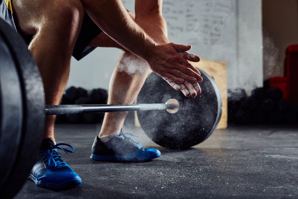 Closeup of weightlifter clapping hands before barbell workout at the gym